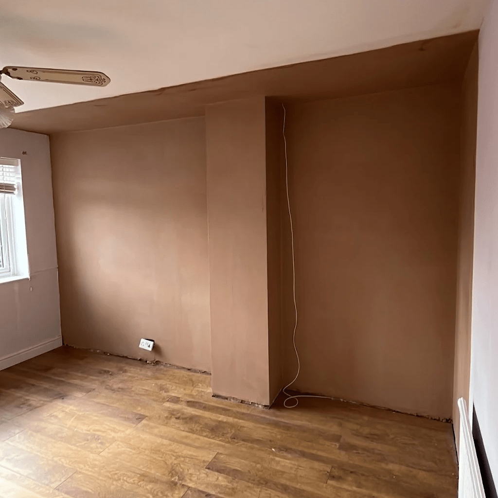 Freshly plastered room walls and ceiling with a bay window.