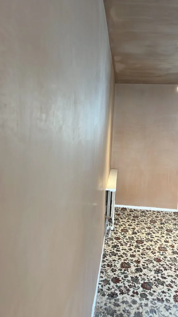 Smooth plaster finish on a living room wall with a patterned carpet and exposed electrical wiring.