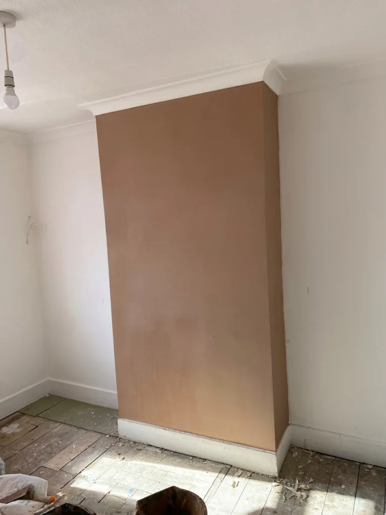 Room with a newly plastered chimney breast and exposed floorboards