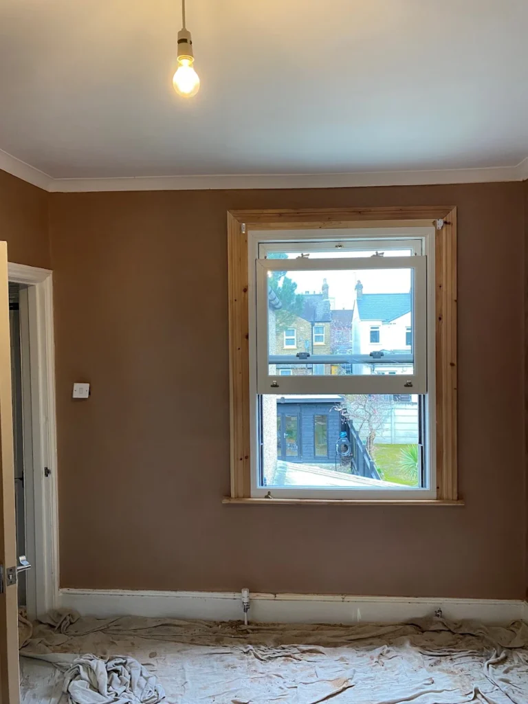 Smooth plastered room walls with a window and protective floor covering