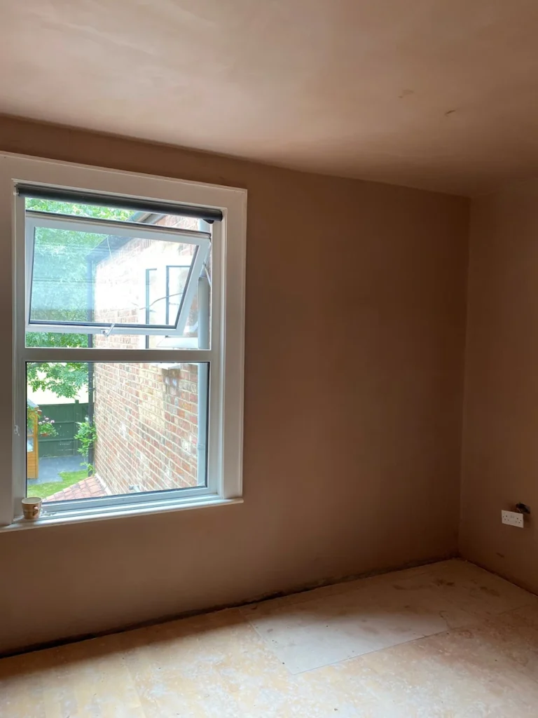 Freshly plastered room with a window and unfinished flooring