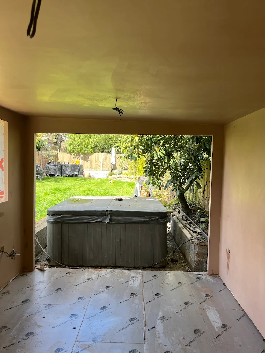 Smooth Touch Plastering interior plastering of a garden room with a large opening overlooking the garden and hot tub.