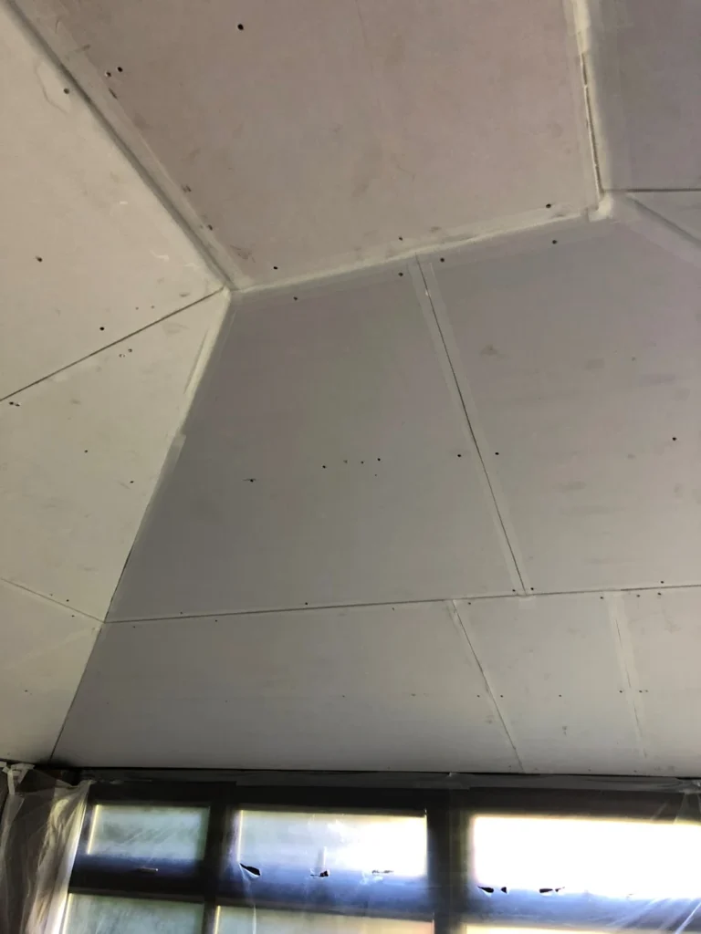 Plasterboard ceiling installation in a room with covered windows